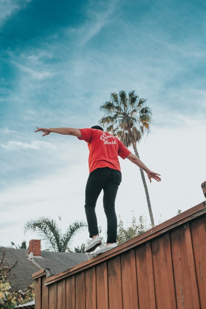 man standing on brown wooden wall during daytime